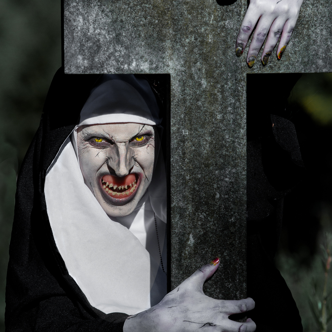 the Nun in a cemetery by a grave stone cross