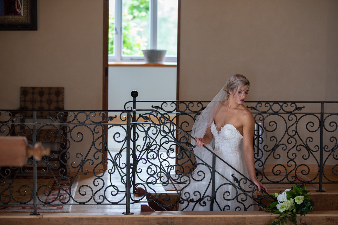 bride looking over he r shoulder down the stairs of the French Country House