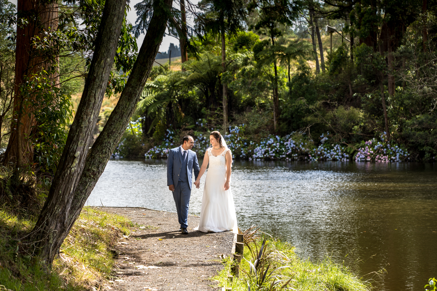 bride and groom walking on a path beside a river at McLaren Falls Park