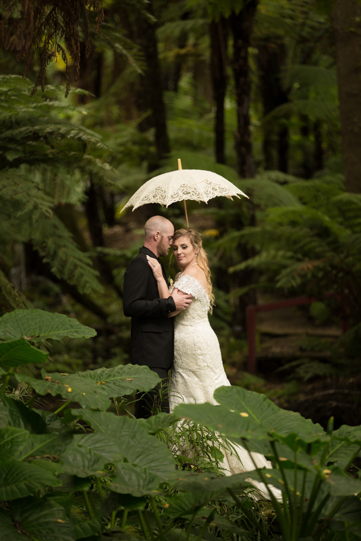 bride and groom under a cream lace umbrella at Fountain Gardens Venue