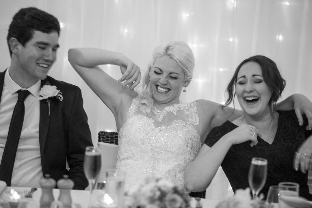 black and white photo of bride and groom at reception having a joke